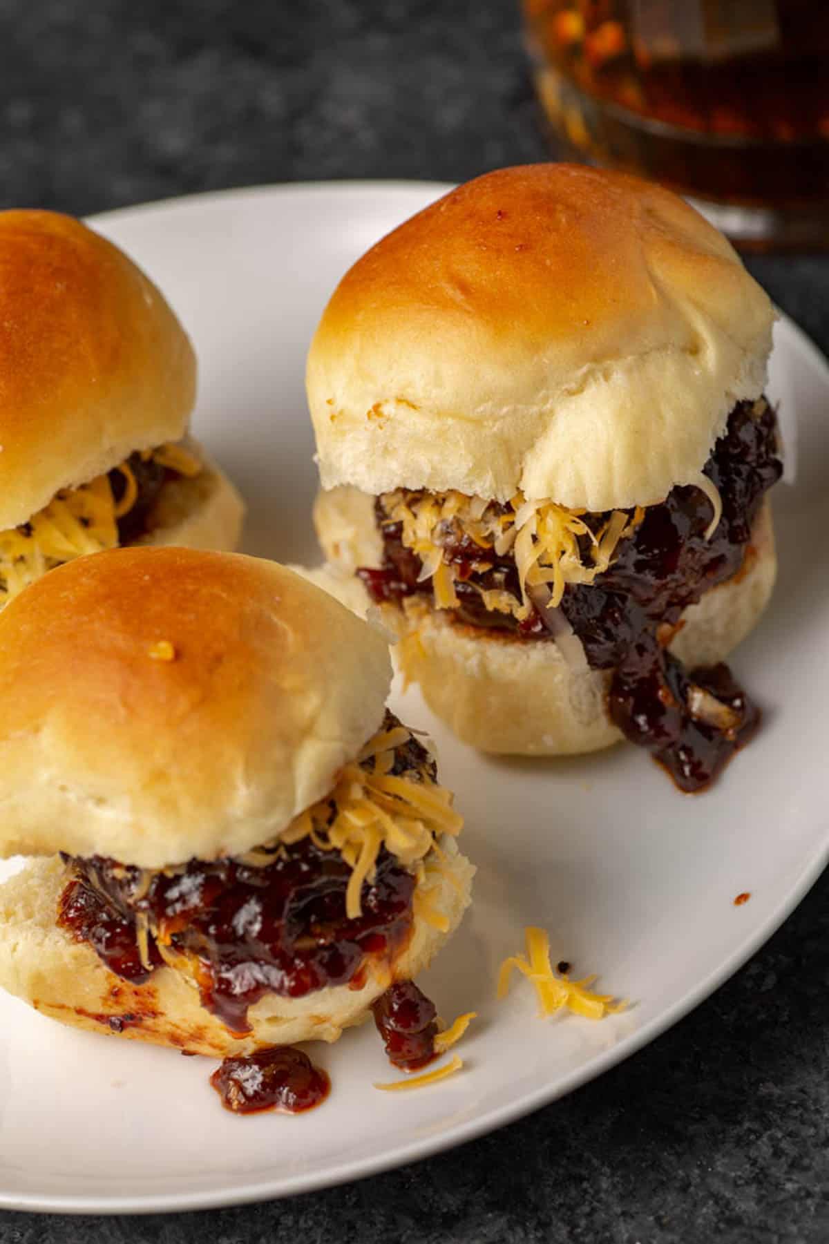 A white platter of bourbon hamburger sliders.