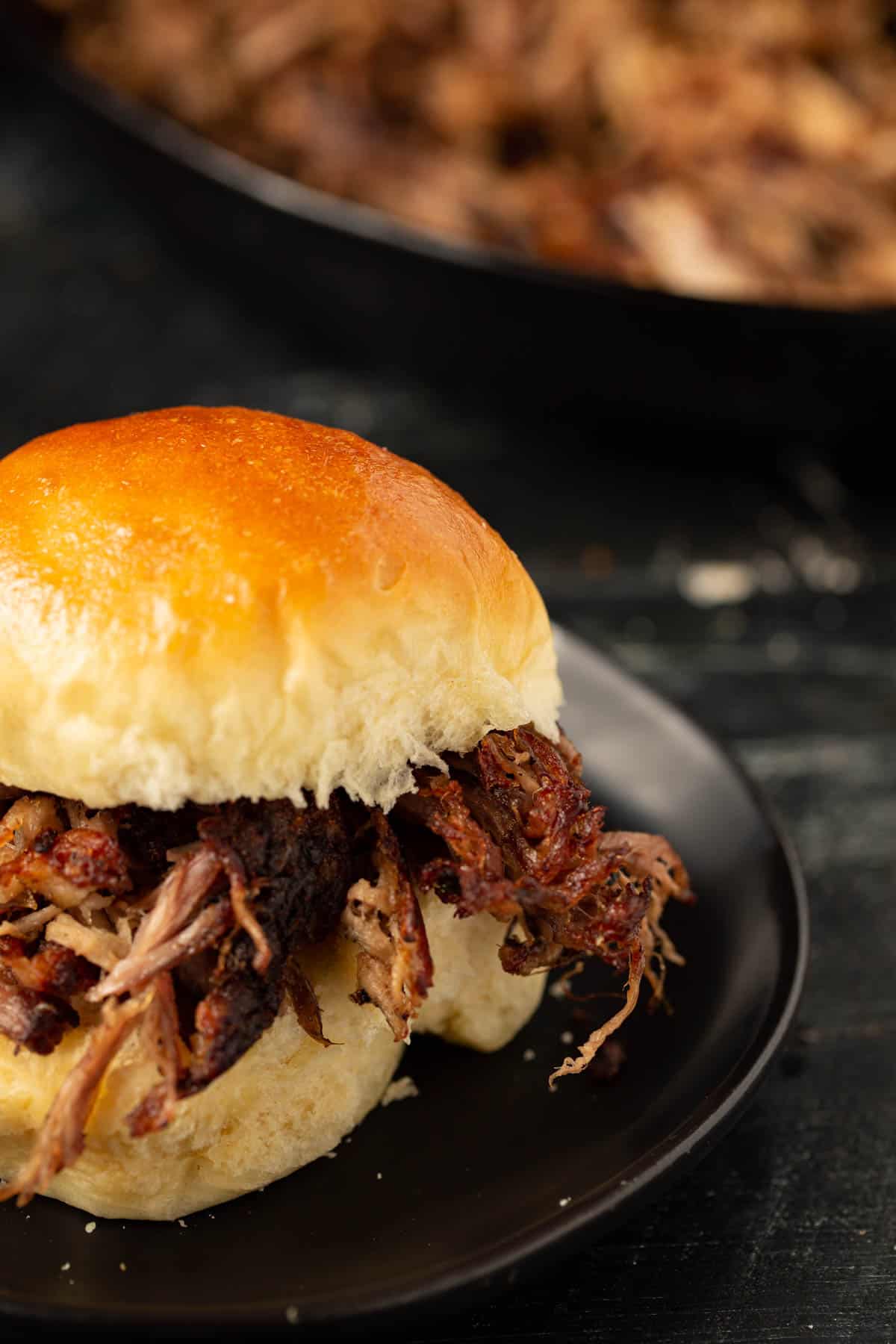 Slow cooked pork stacked on a Hawaiian roll.