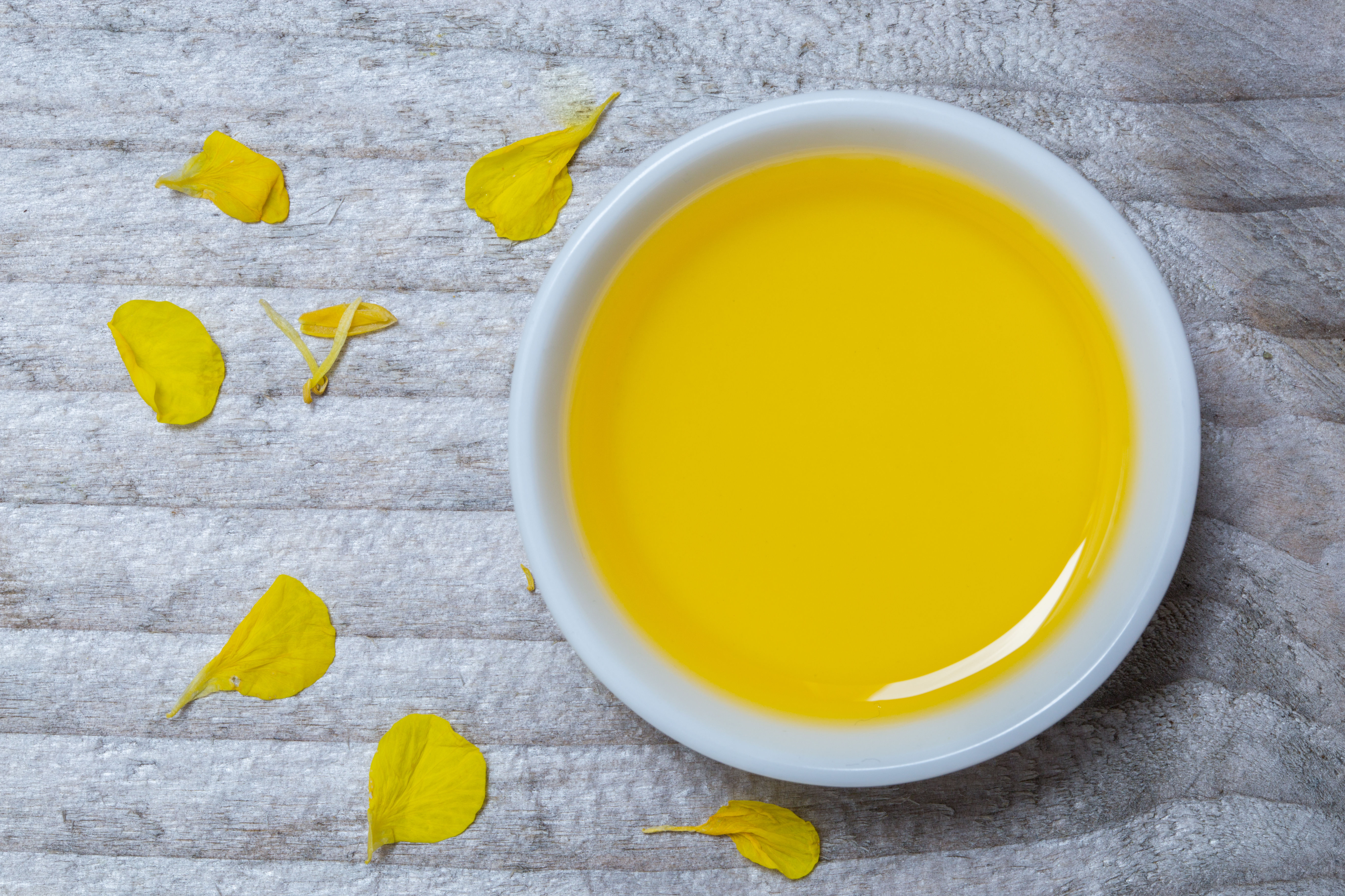 Rapeseed oil concept in front of gray wood