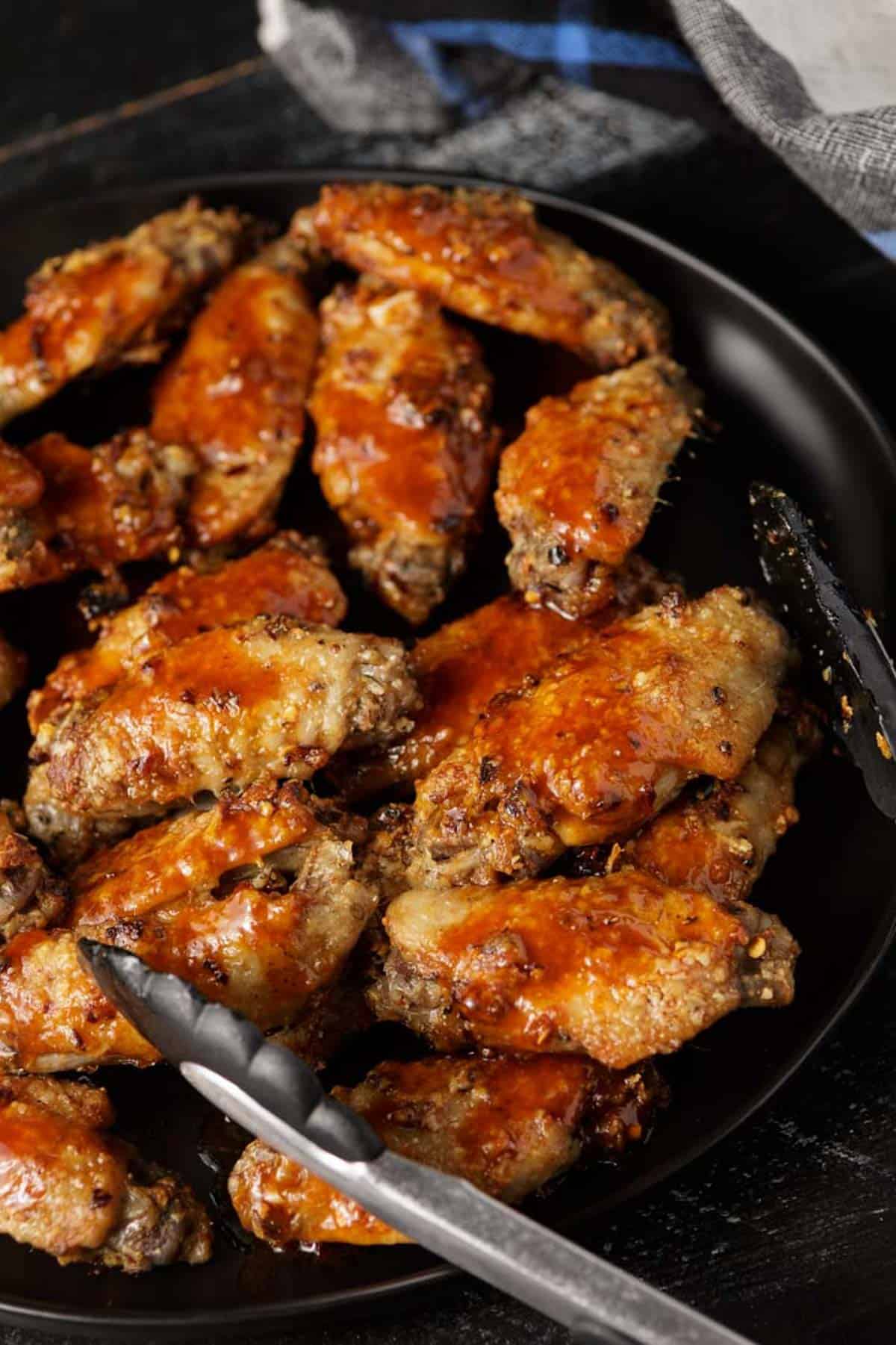 A white platter full of grilled chicken drumsticks and thighs.