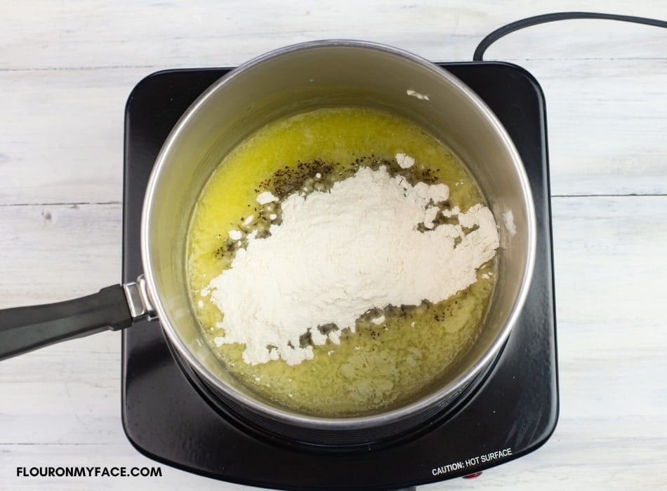 The beginning of making a roux by adding flour, salt, and pepper to melted butter.