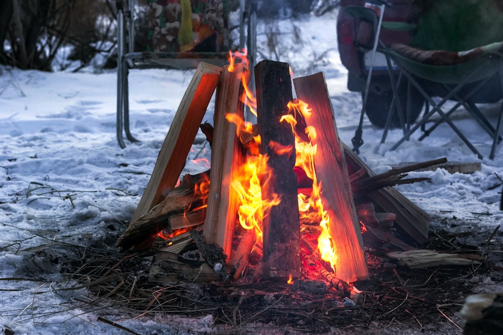 A hot burning campfire on snowy ground at dusk