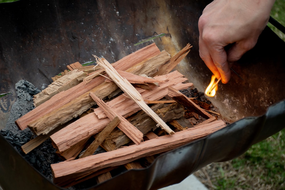 Starting the campfire in a firepit with kindling and safety matches.