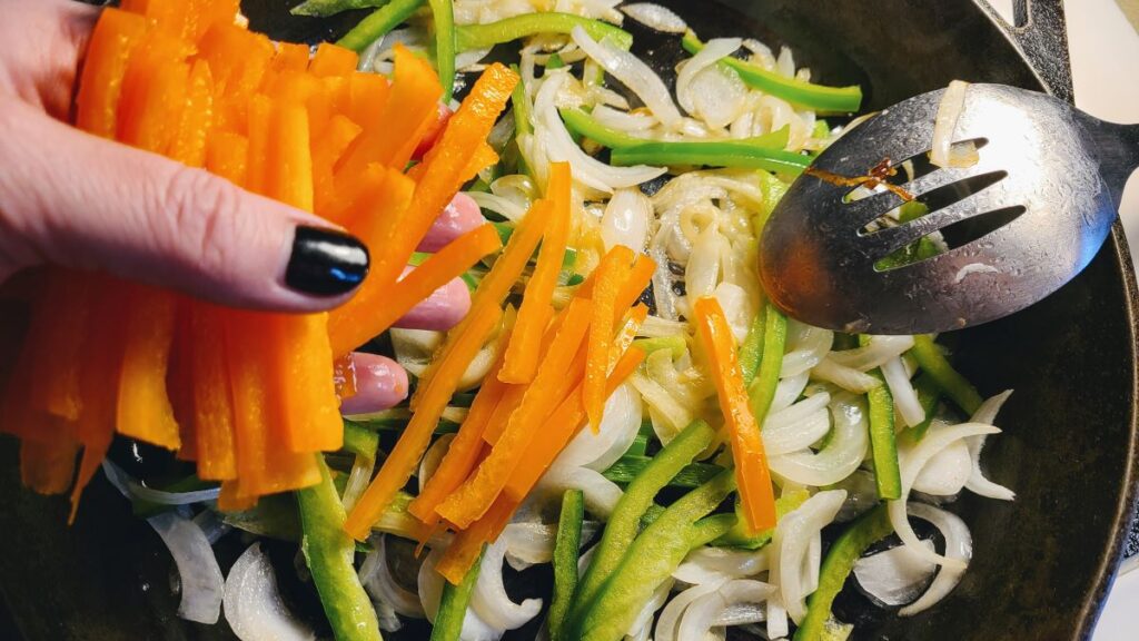 sauteeing onions and peppers in a cast iron from How To Cut Onions And Peppers Into Strips For Fajitas 
