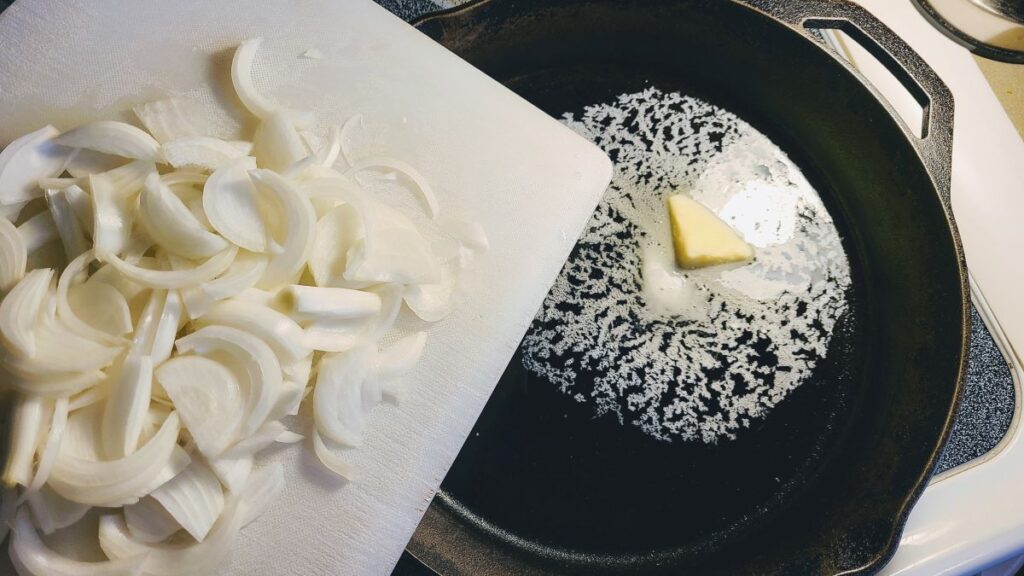 putting onion into a cast iron pan with butter