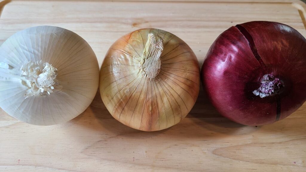 wooden cutting board with 3 onions