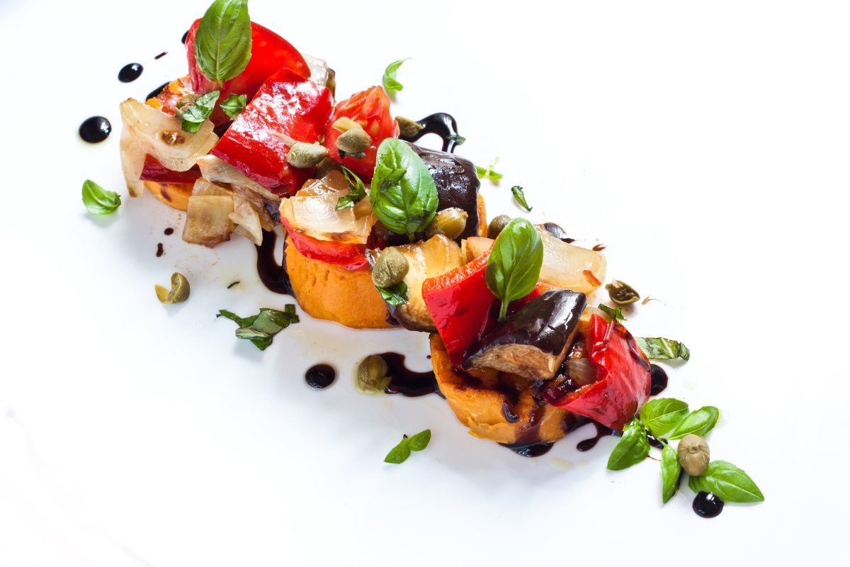 A classic ratatouille of sliced rounds of colorful vegetables arranged in a circular fashion in a oval casserole dish.