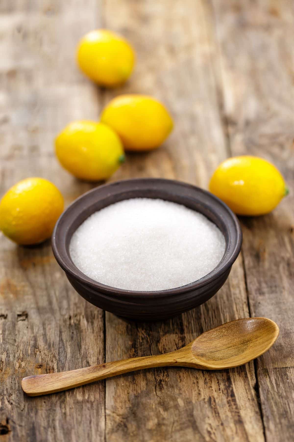 a bowl of citric acid beside several lemons.