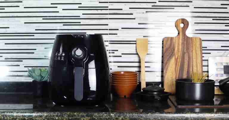 Black air fryer on a counter with other cooking tools