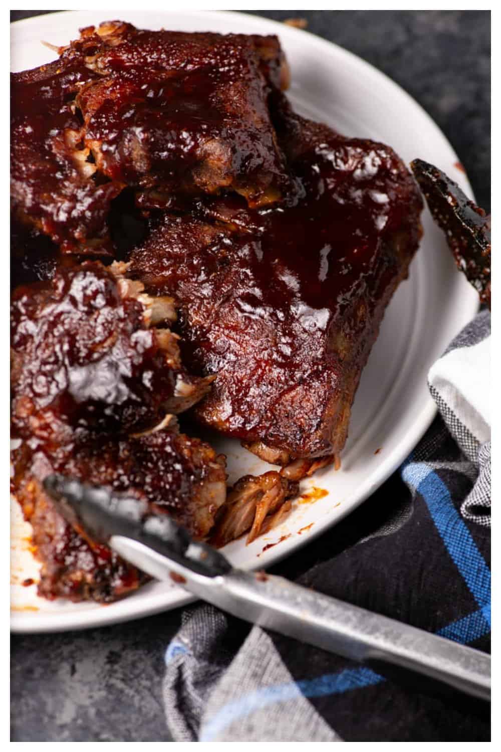 A platter of slow cooker ribs with a napkin and prongs