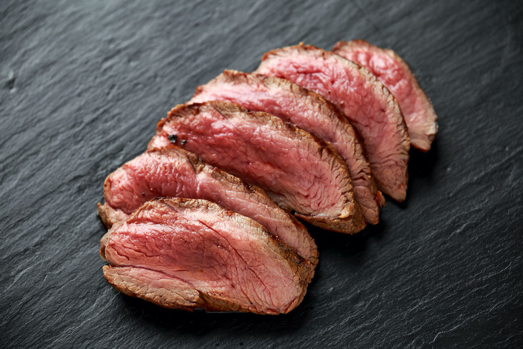 Filet of elk fanned out across a plate, cooked medium rare